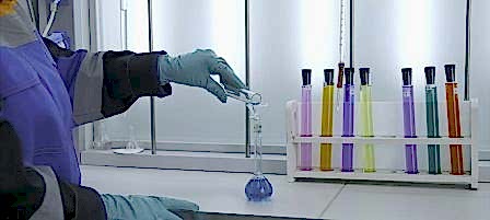 Woman conducts laboratory experiments and analyzes. Clip. Woman looks at chemical liquid in laboratory. Industrial laboratory with workers and chemicals in test tubes.